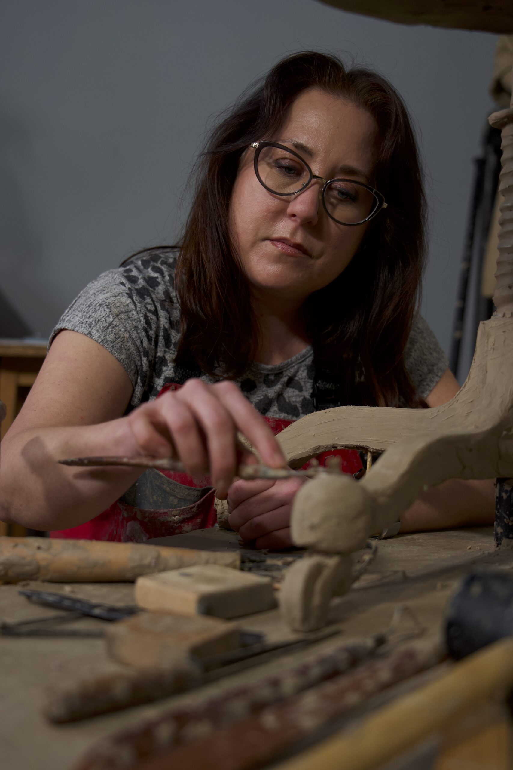 Sarah uses wooden tools to sculpt the details of a larger-than-life-size sculpture.