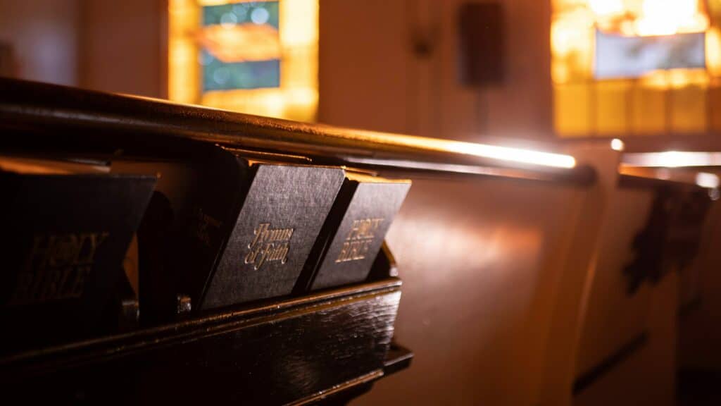 An image of the back of a church pew with two hymnals.