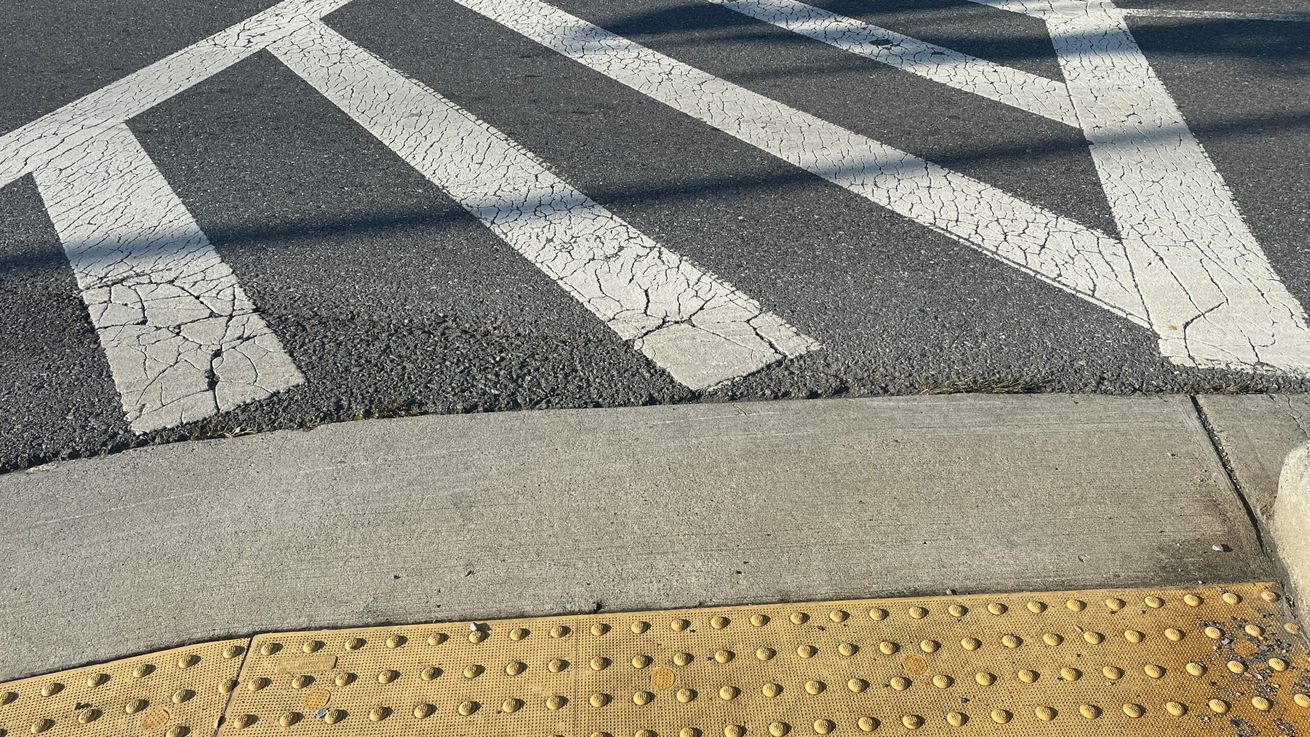 An image of a crosswalk with a yellow ADA compliant curb. 